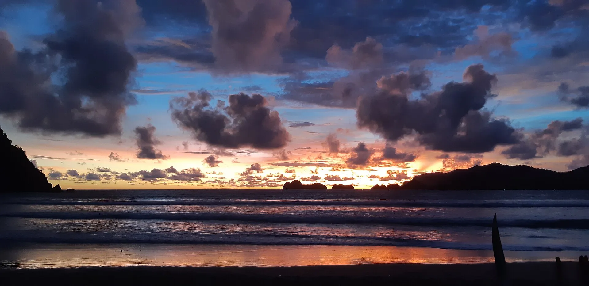 Siluet bukit Pulau Merah menghadap laut saat matahari terbenam di Banyuwangi.